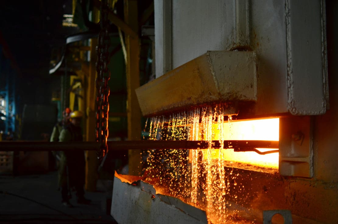 Steel quenching at high temperature in industrial furnace at the workshop of a forge plant. 