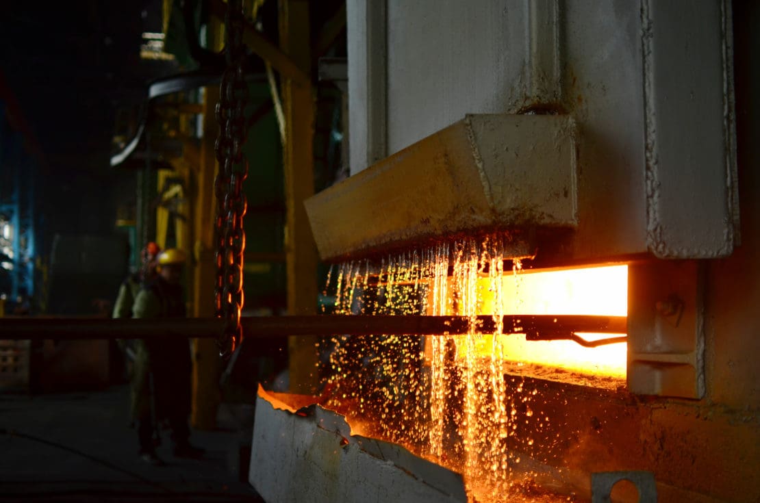Steel quenching at high temperature in industrial furnace at the workshop of a forge plant.